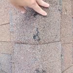 Roof repair Twin Cities – First Impressions Exteriors inspector pointing out hail damage to ridge cap shingles on Golden Valley Minnesota home during storm damage assessment