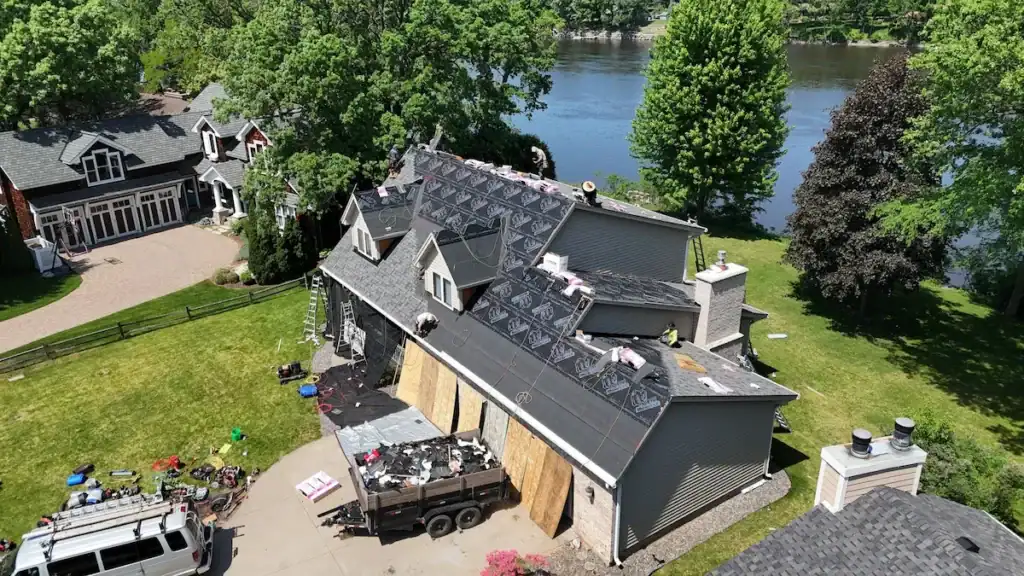 Roof replacement in progress on a lakefront Minnesota home by First Impressions Exteriors