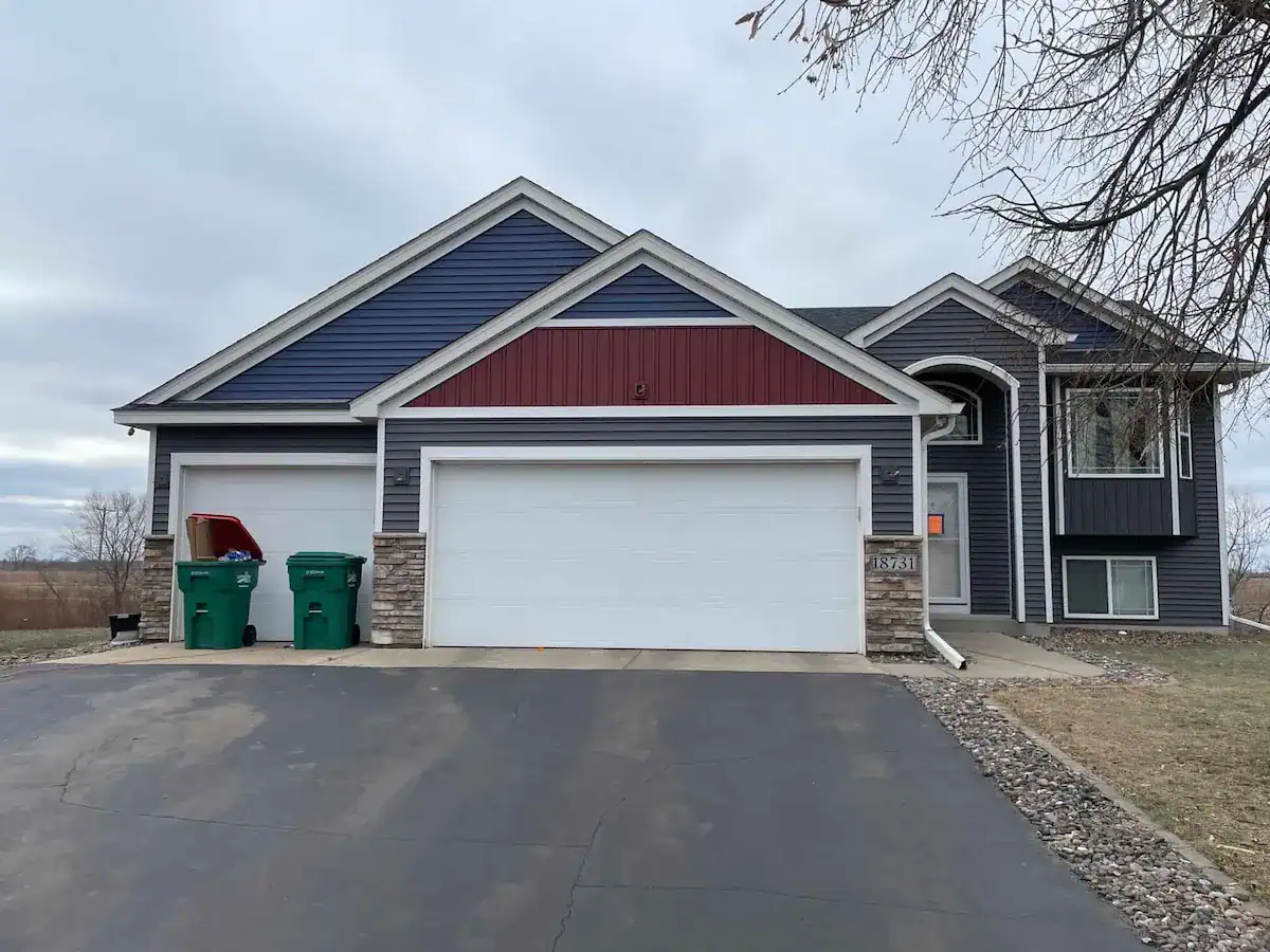 After photo of Big Lake Minnesota home with new navy blue lap siding, red board-and-batten accents, and new asphalt shingle roof installed by First Impressions Exteriors