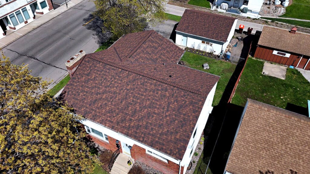 Aerial view of completed residential roof replacement with brown asphalt shingles in Minnesota.