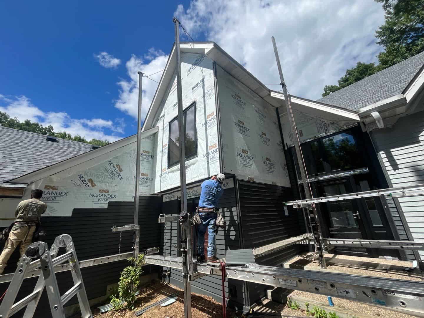 Siding crew installing dark siding from scaffolding on a White Bear Lake home