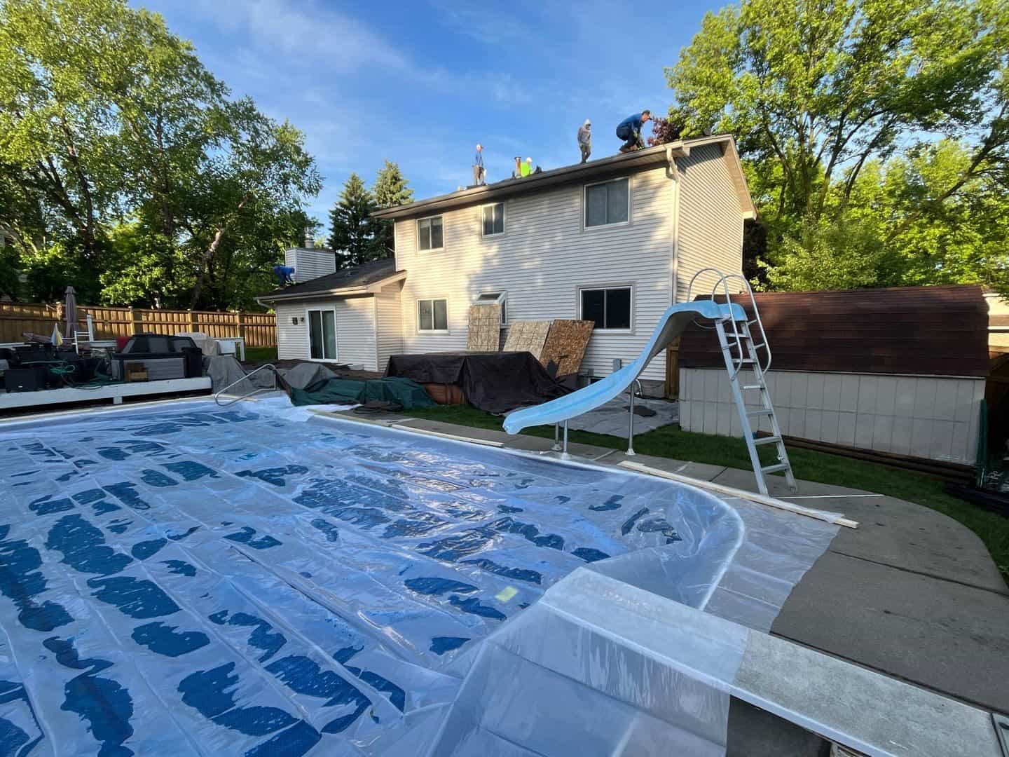 Backyard pool protected with poly sheeting during a Plymouth, MN roof replacement