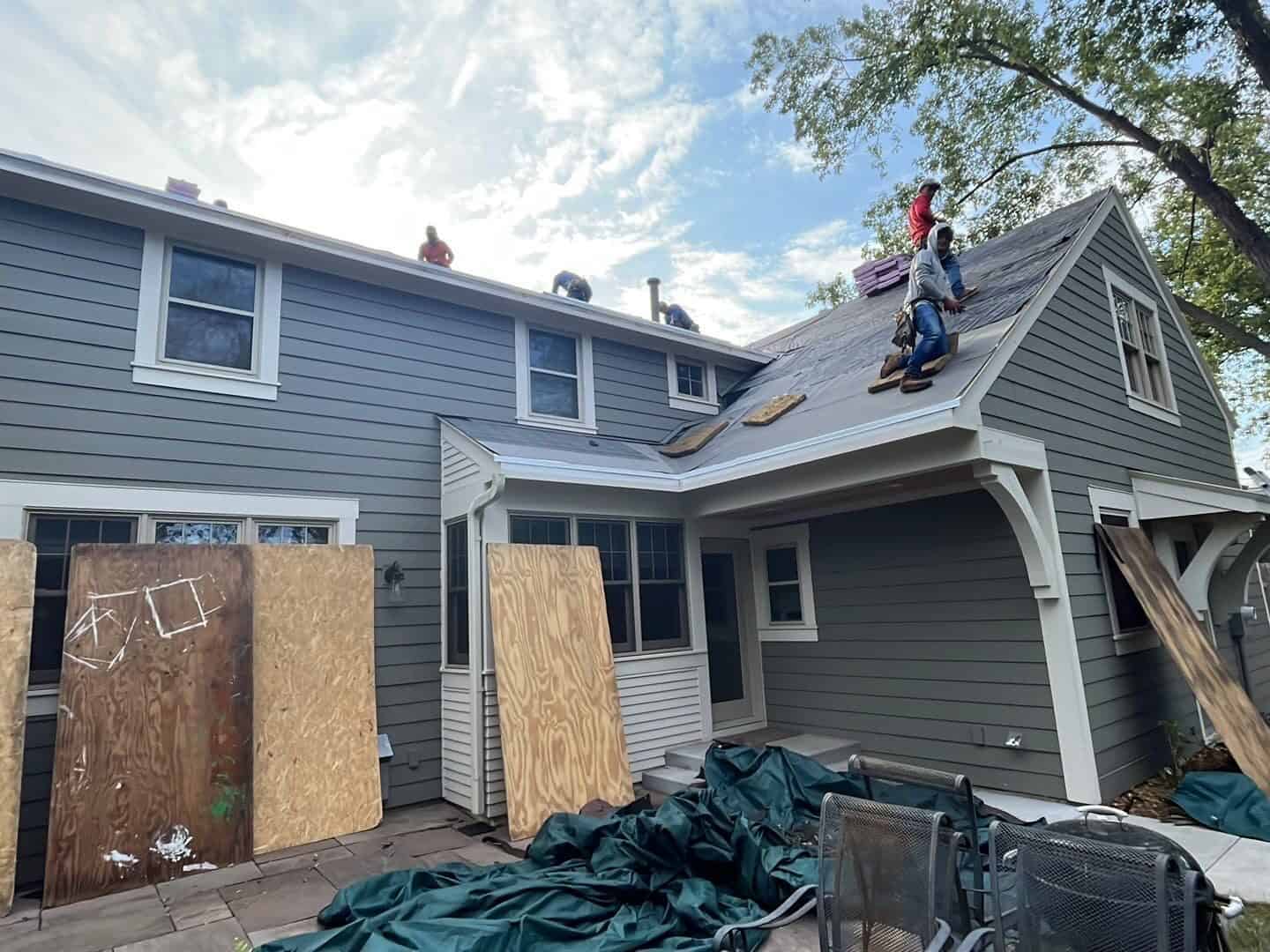 Crew installing shingles with the home protected during a Golden Valley, MN roof replacement