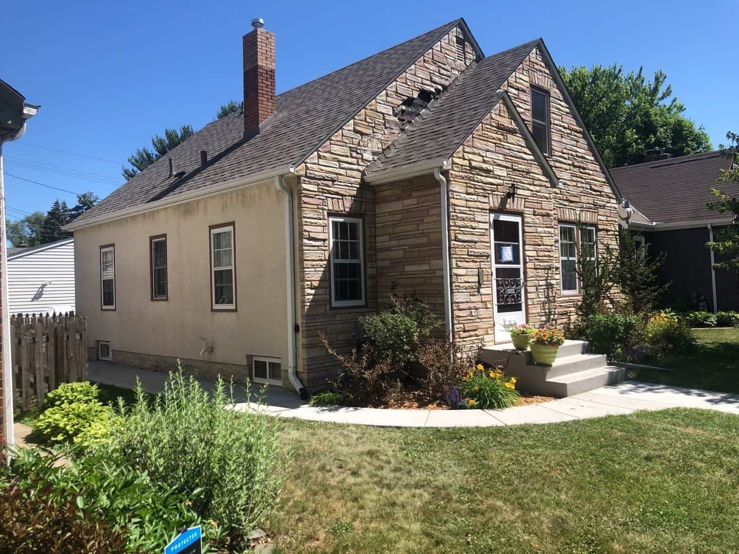 St. Paul, MN stone home before its roof replacement, with damage visible on the old roof