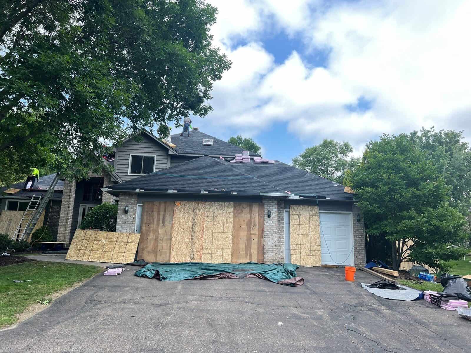 Home protected with boards and tarps during a Plymouth, MN roof replacement